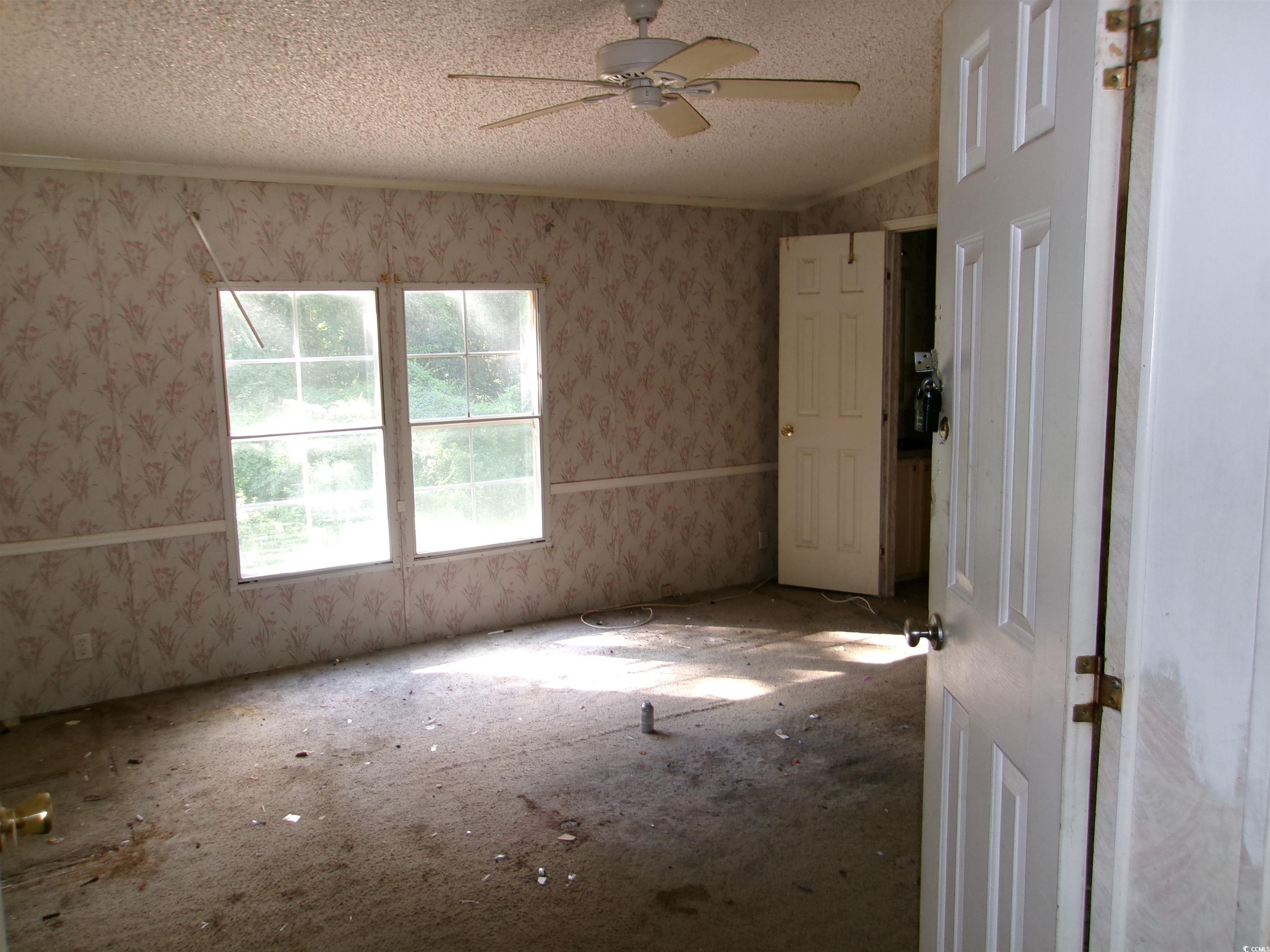 4261 Blake Road Myrtle Beach, SC 29588 - Photo 5 of 11 Spare room with ceiling fan, wallpapered walls, and a textured ceiling