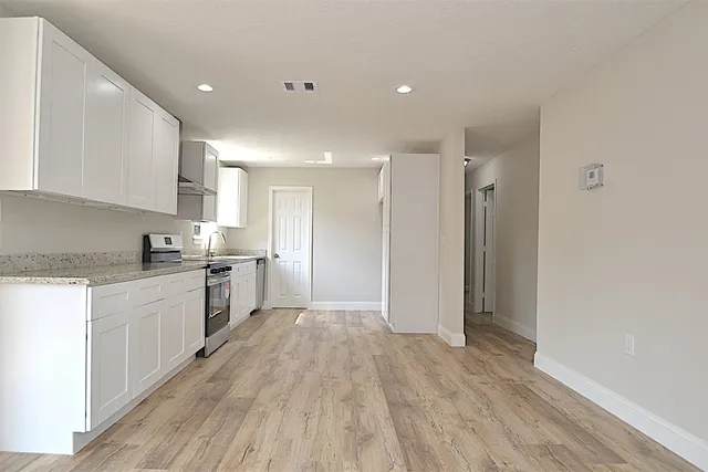 a large kitchen with a wooden floor and white stainless steel appliances