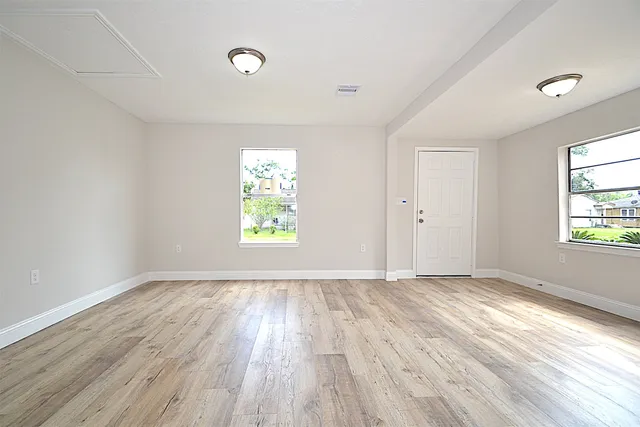 an empty room with wooden floor and windows