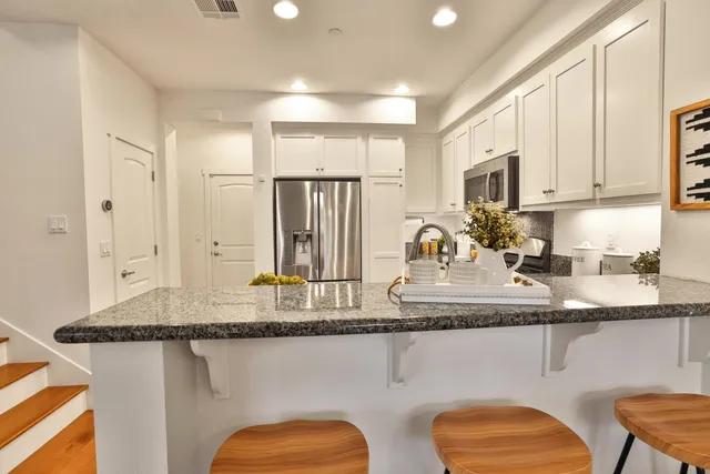 a kitchen with stainless steel appliances granite countertop a sink a stove cabinets and a dining table