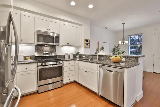 a kitchen with stainless steel appliances granite countertop a stove a sink and a refrigerator