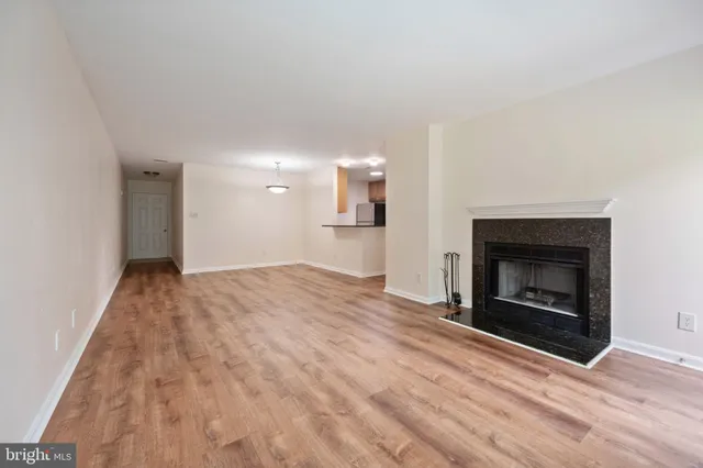 a view of empty room with a fireplace and wooden floor