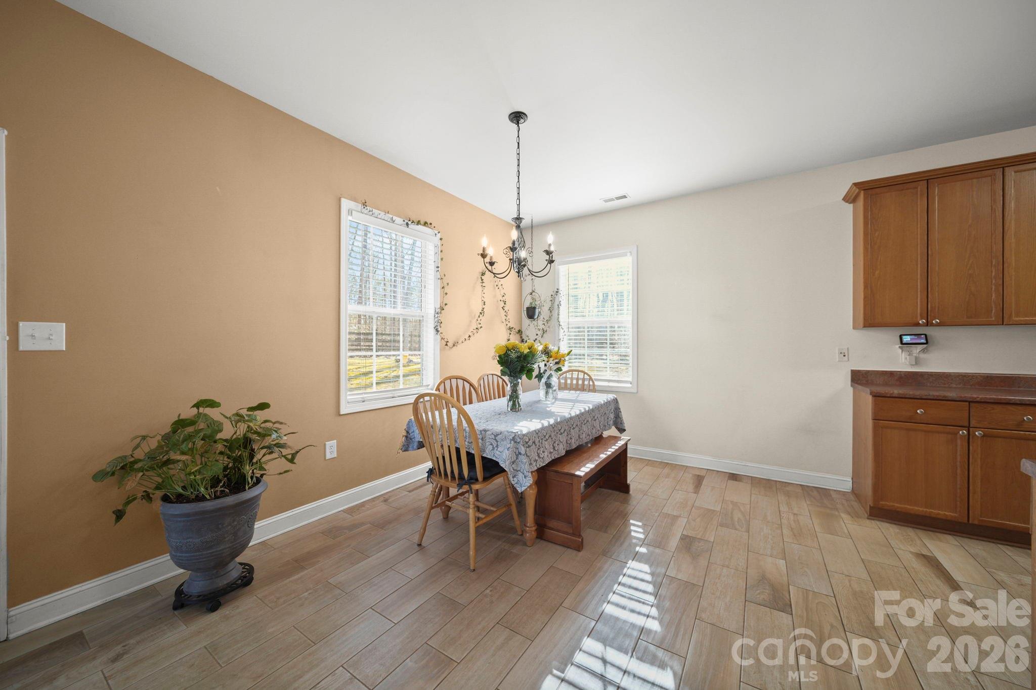 3035 Proverbs Court Monroe, NC 28110 - Photo 9 of 39 a dining room with furniture potted plants and wooden floor