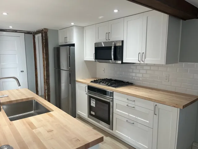 a kitchen with stainless steel appliances kitchen island granite countertop a refrigerator sink and white cabinets