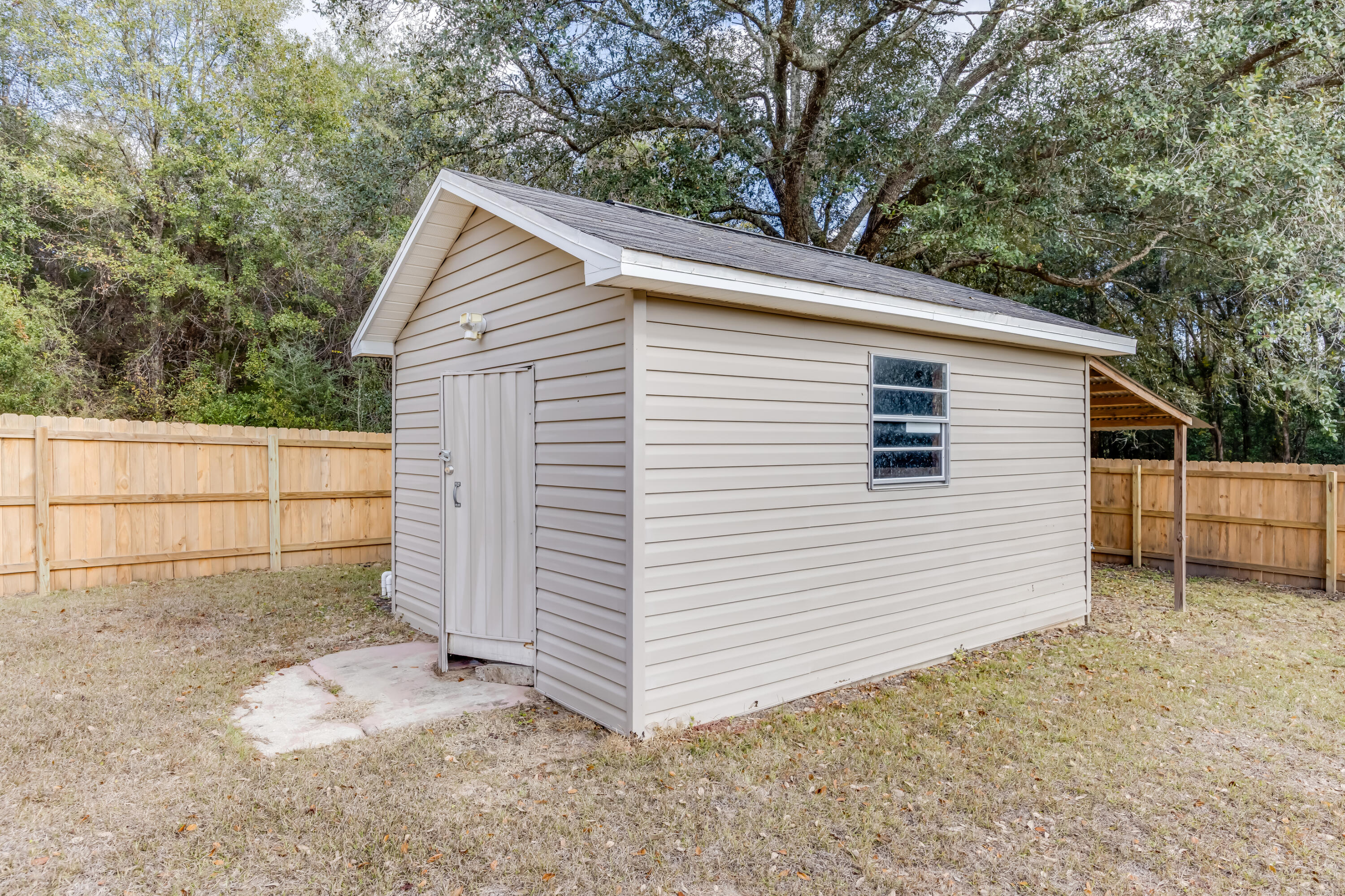 3005 Lillie Street Crestview, FL 32539 - Photo 39 of 46 a view of a white house with large trees and wooden fence