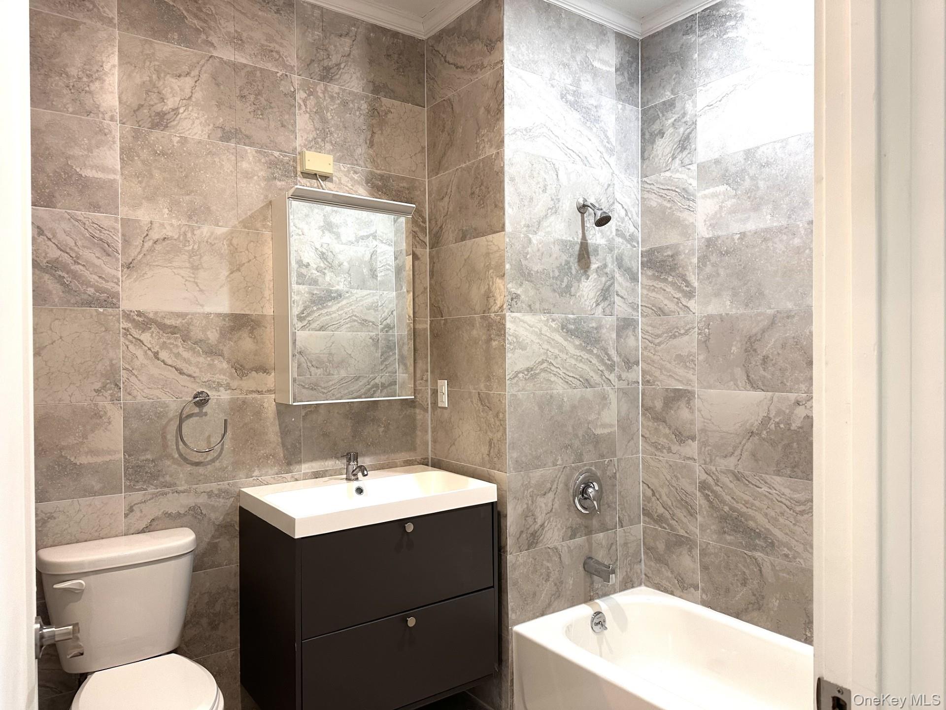 362 West Merrick Road, Unit 101 Valley Stream, NY 11580 - Photo 2 of 9 Full bath with tile walls, vanity, bathtub / shower combination, and ornamental molding