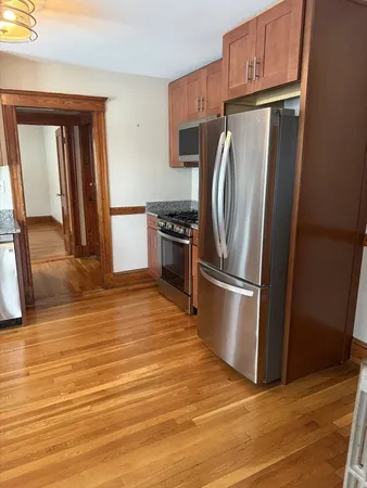 a kitchen with stainless steel appliances granite countertop a refrigerator a stove and a sink with wooden floor