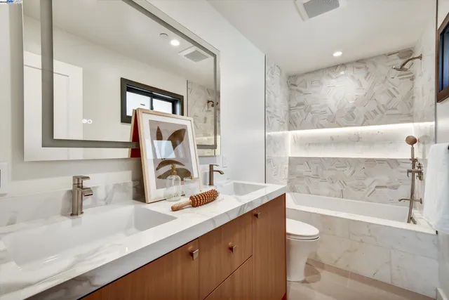 a bathroom with a granite countertop sink mirror toilet and bathtub