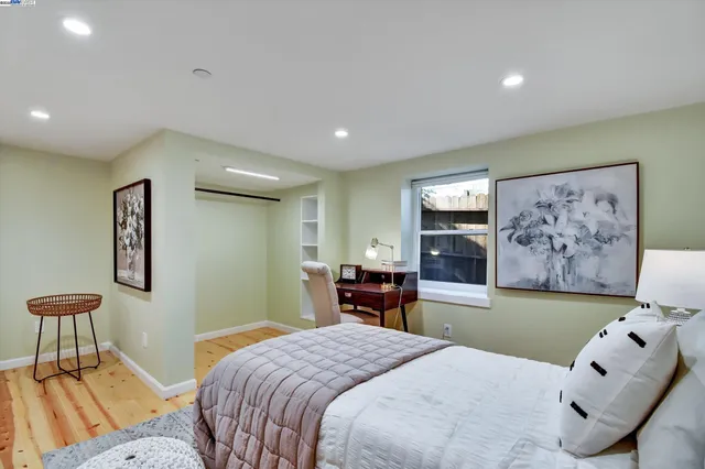 a bedroom with a bed and a chair with painting on the wall