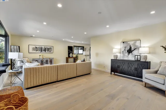 a living room with furniture and a dining table with wooden floor