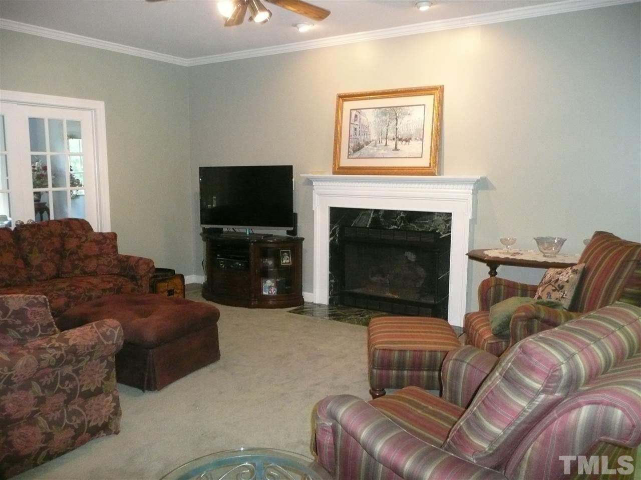 2604 Sunnystone Way Raleigh, NC 27613 - Photo 7 of 25 a living room with furniture a flat screen tv and a fireplace