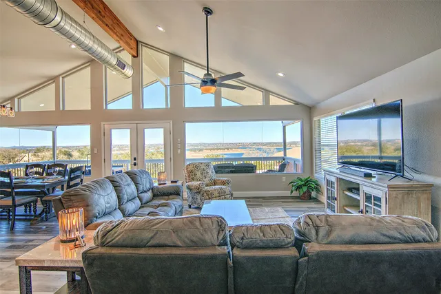 a living room with furniture a flat screen tv and a large window
