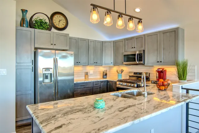 a kitchen with stainless steel appliances a sink dishwasher a stove a microwave oven with cabinets and wooden floor