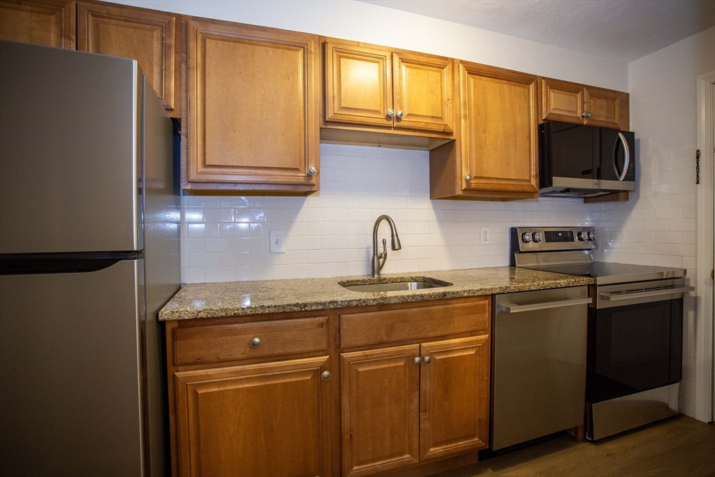 5 Washington Street, Unit C9 Reading, MA 01867 - Photo 9 of 21 a kitchen with stainless steel appliances granite countertop a refrigerator stove top oven a sink and dishwasher