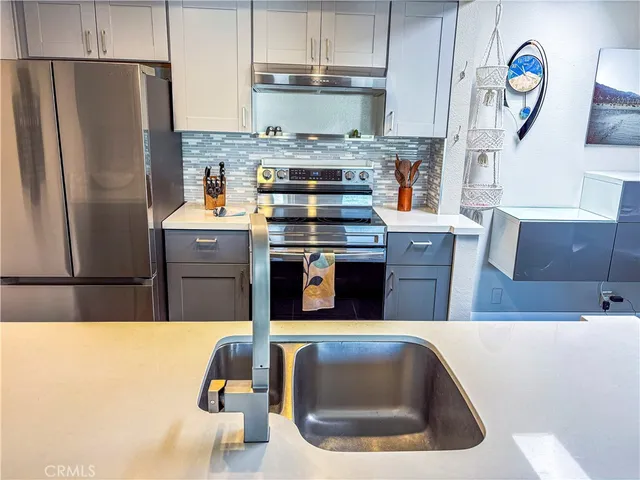 a kitchen with stainless steel appliances granite countertop a sink a stove a refrigerator and a refrigerator