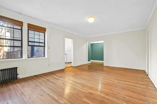 a view of an empty room with wooden floor and a window