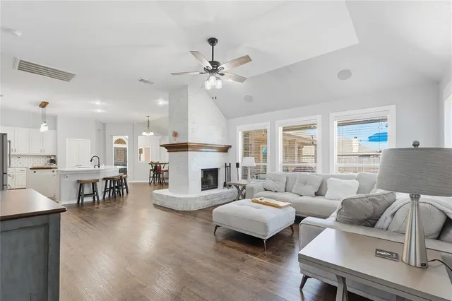 a view of a livingroom with a flat screen tv wooden floor and a ceiling fan