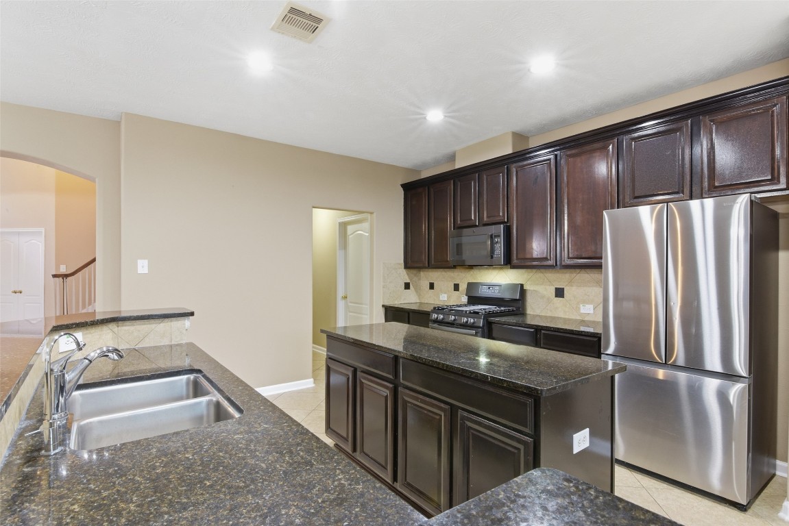 24938 Crystal Stone Lane Katy, TX 77494 - Photo 16 of 50 a kitchen with granite countertop a refrigerator stove and sink