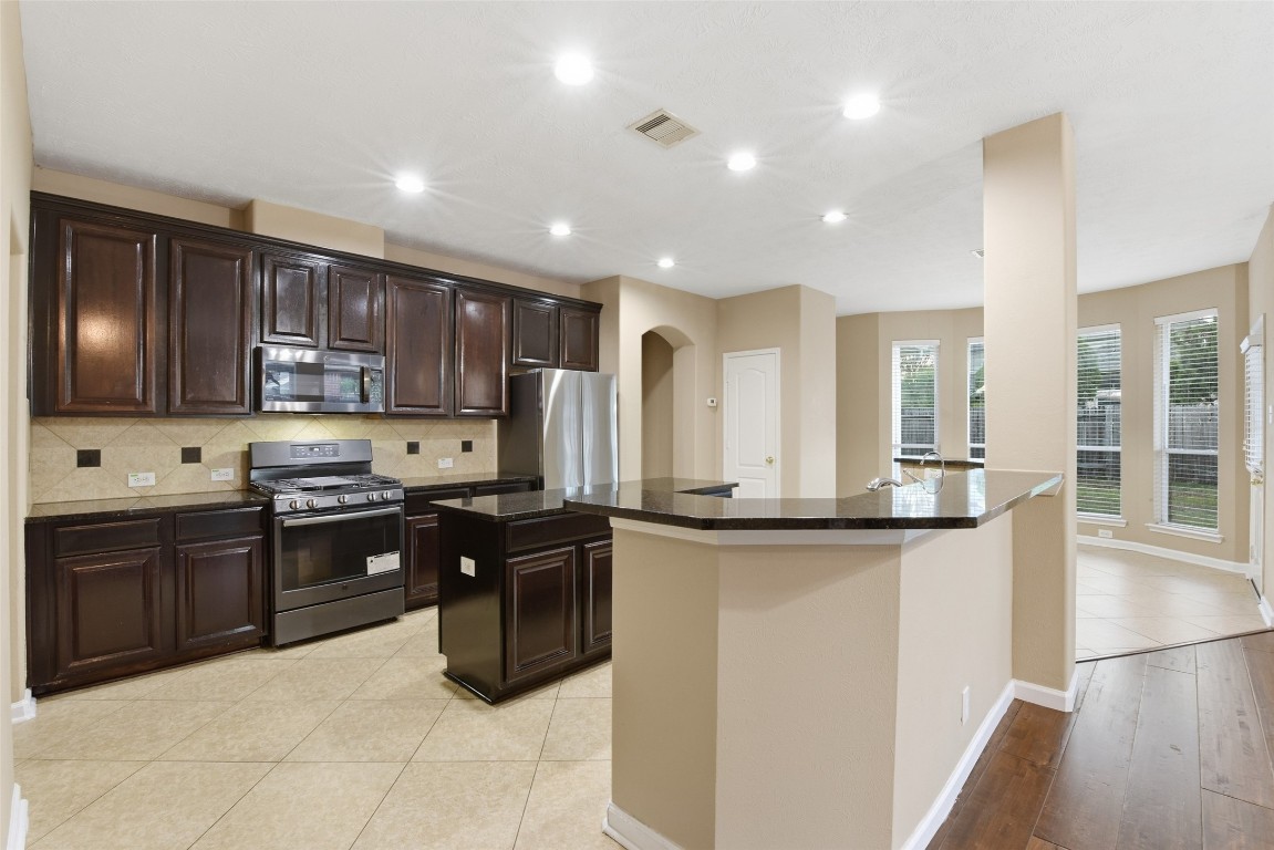 24938 Crystal Stone Lane Katy, TX 77494 - Photo 21 of 50 a kitchen with stainless steel appliances granite countertop wooden cabinets a stove a sink and dishwasher