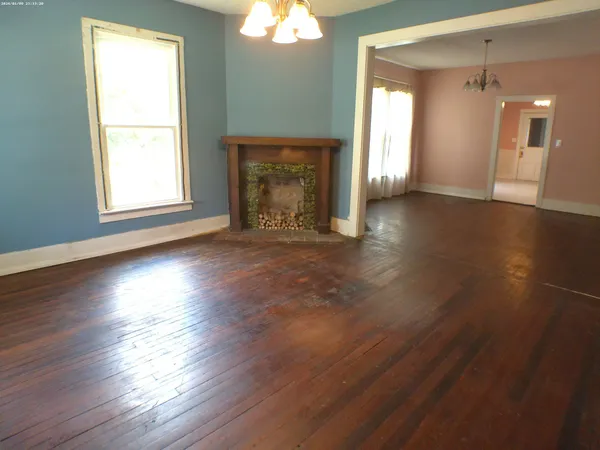 an empty room with wooden floor a fireplace and windows