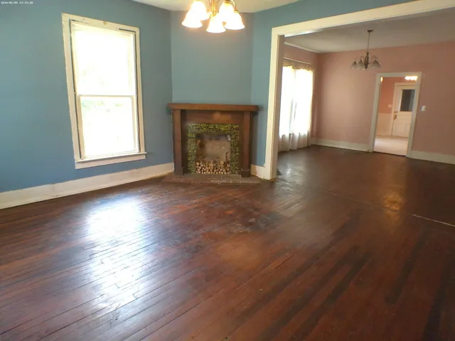 an empty room with wooden floor a fireplace and windows