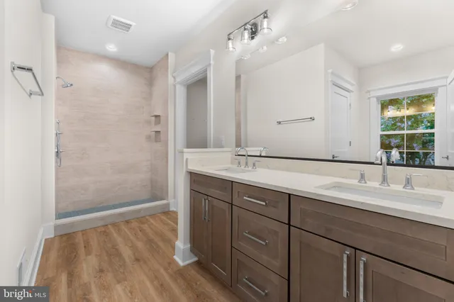 a bathroom with a double vanity sink a mirror and shower