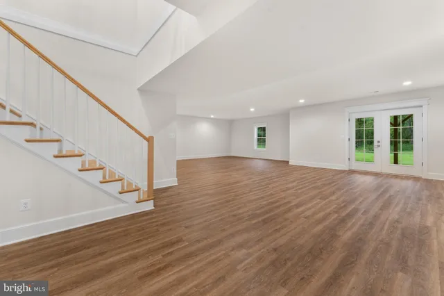 a view of an empty room with wooden floor and stairs