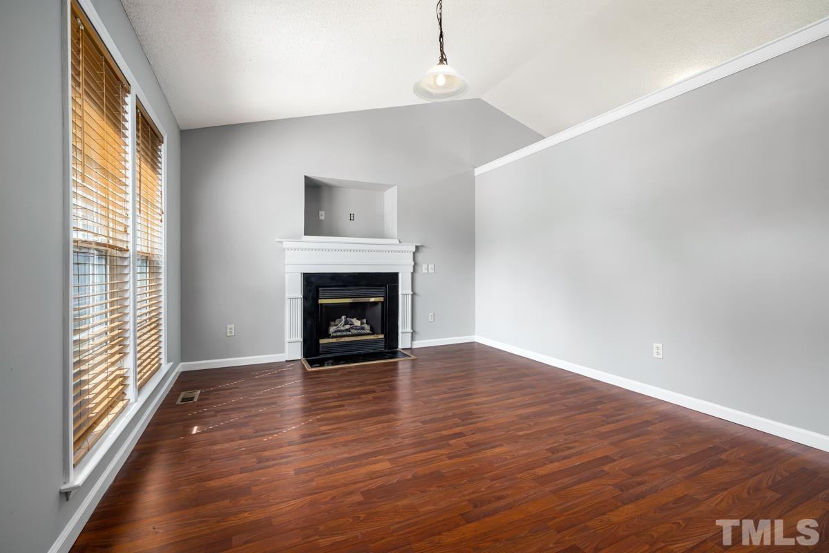 4516 Eider Court Raleigh, NC 27616 - Photo 8 of 28 a view of empty room with wooden floor and fireplace