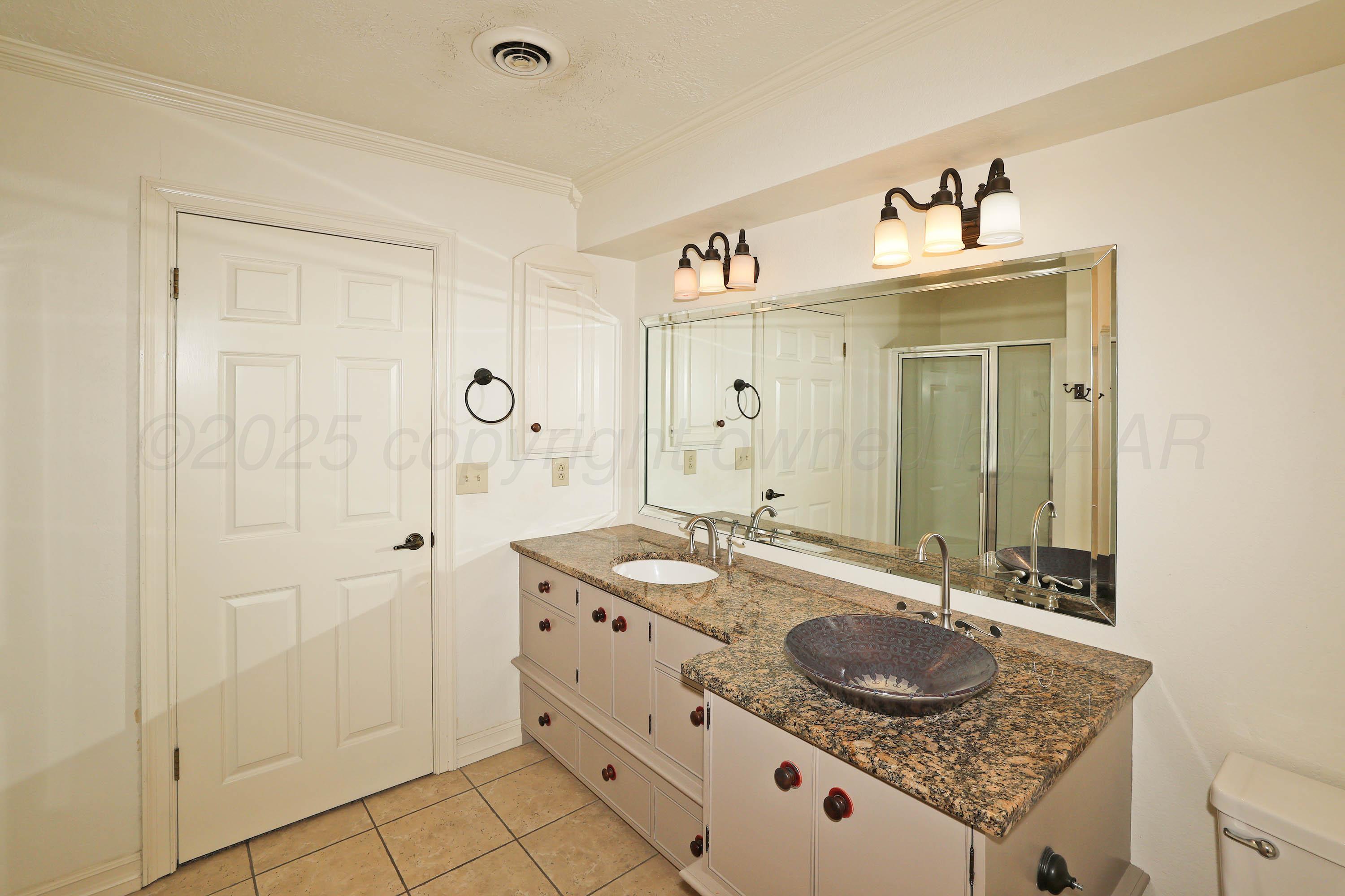 1615 South Bryan Street, Unit 19 Amarillo, TX 79102 - Photo 37 of 53 a bathroom with a granite countertop sink a mirror and a shower