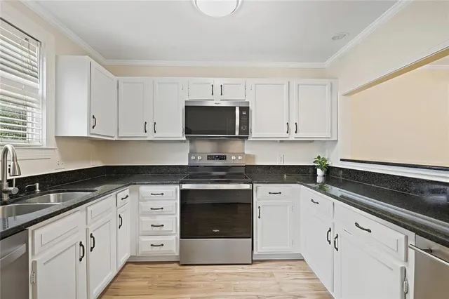 a kitchen with granite countertop white cabinets and black appliances