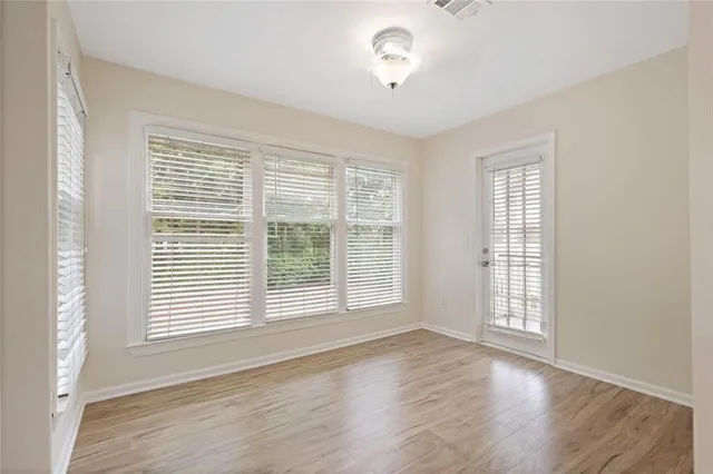 a view of an empty room with a window and wooden floor