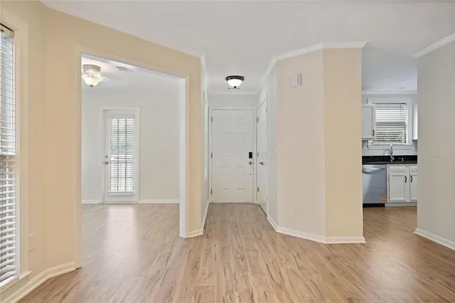 a view of empty room with wooden floor and kitchen