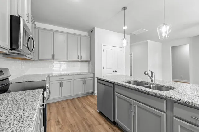 a kitchen with stainless steel appliances granite countertop a sink a stove a oven a refrigerator with white cabinets and wooden floor