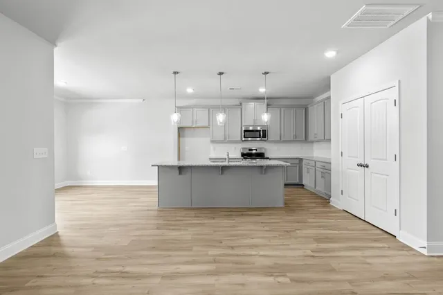 a large kitchen with stainless steel appliances kitchen island a large counter top and a wooden floors