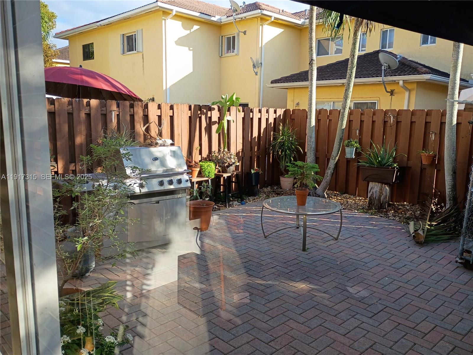 13274 Southwest 142nd Terrace, Unit 13274 Miami, FL 33186 - Photo 22 of 32 a view of a patio with a table and chairs under an umbrella