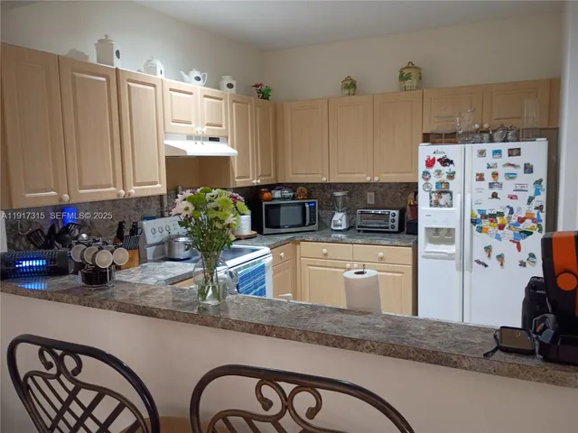 a kitchen with kitchen island granite countertop a refrigerator and a stove top oven
