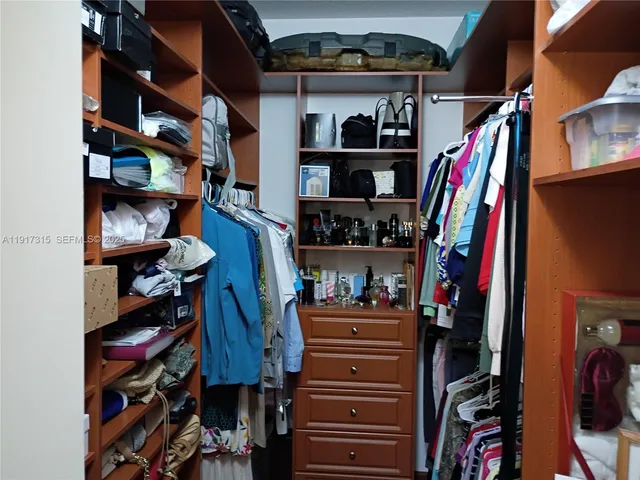 a view of walk in closet with clothes and shoes