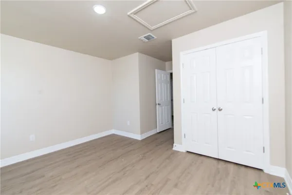 a view of an empty room with wooden floor and a ceiling fan