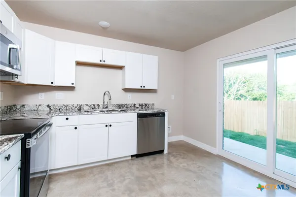 a kitchen with granite countertop white cabinets and white appliances