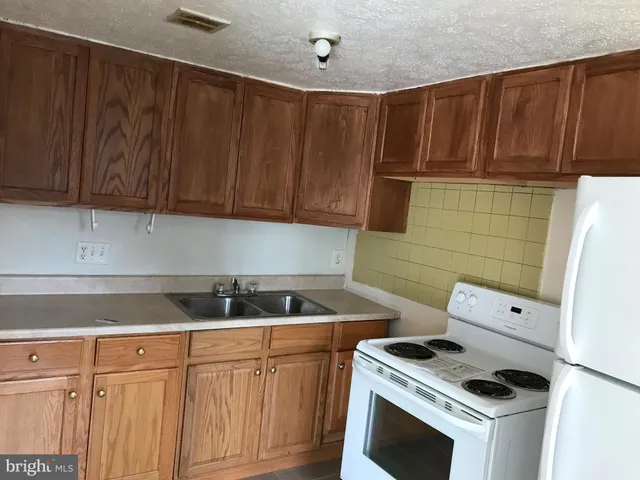 a kitchen with granite countertop wood cabinets and white appliances