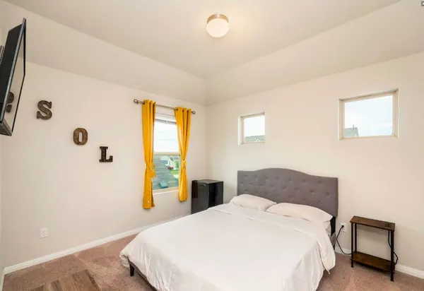 a bedroom with a bed and a flat tv screen on dresser