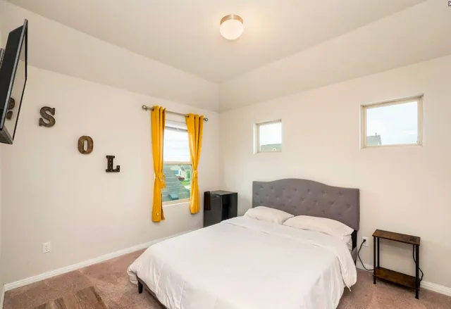a bedroom with a bed and a flat tv screen on dresser