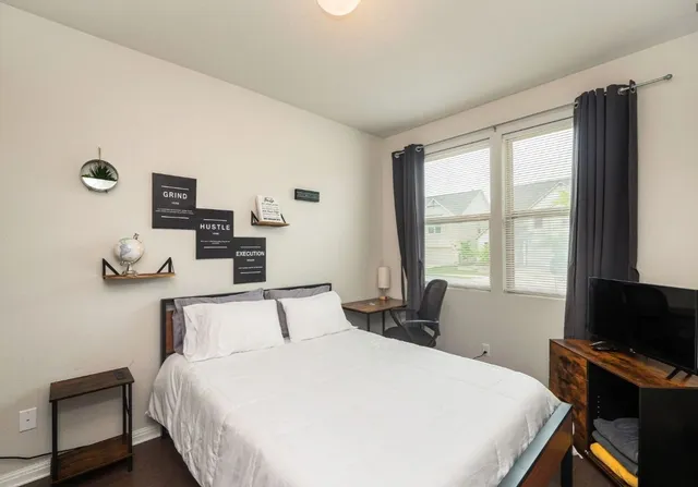 a bedroom with bed and two windows