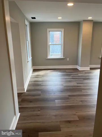 a view of an empty room with wooden floor and stairs