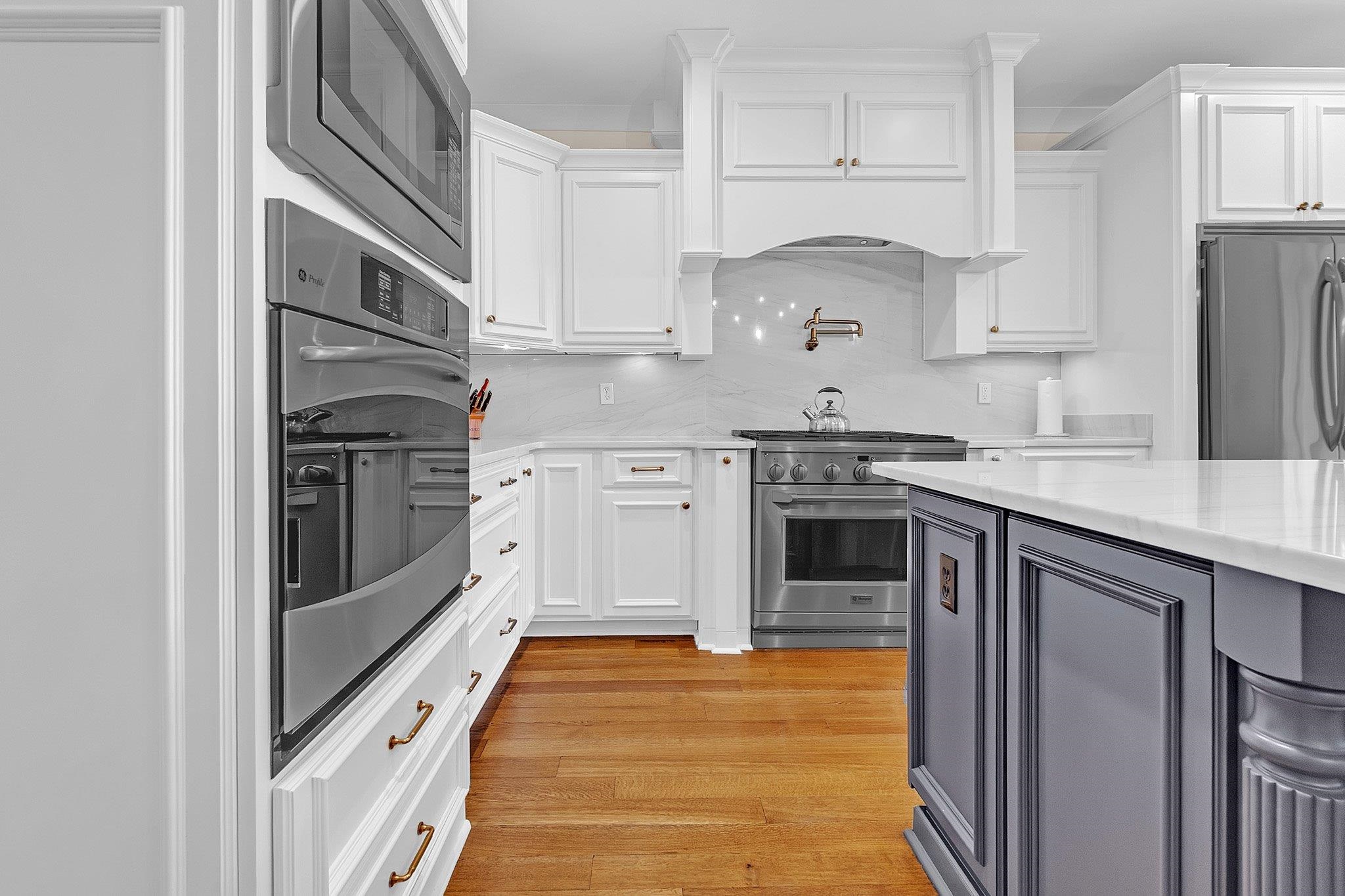 3246 North Hartwell Ridge Drive Collierville, TN 38017 - Photo 20 of 40 Kitchen featuring white shaker cabinetry, stainless steel appliances, a built-in wall oven and microwave, a white range hood, and a gray island with a white countertop