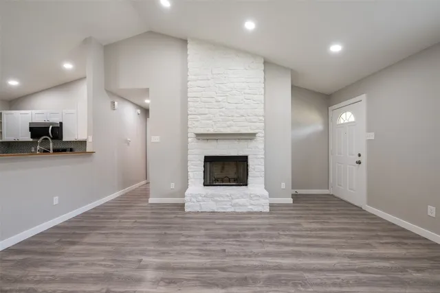 a view of a big room with wooden floor and a kitchen