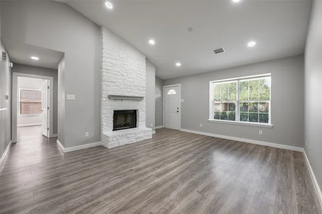 a view of a kitchen and an empty room with wooden floor