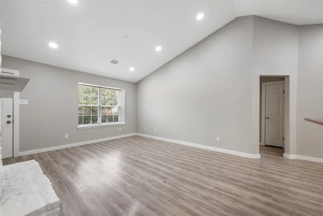 an empty room with wooden floor and a fireplace