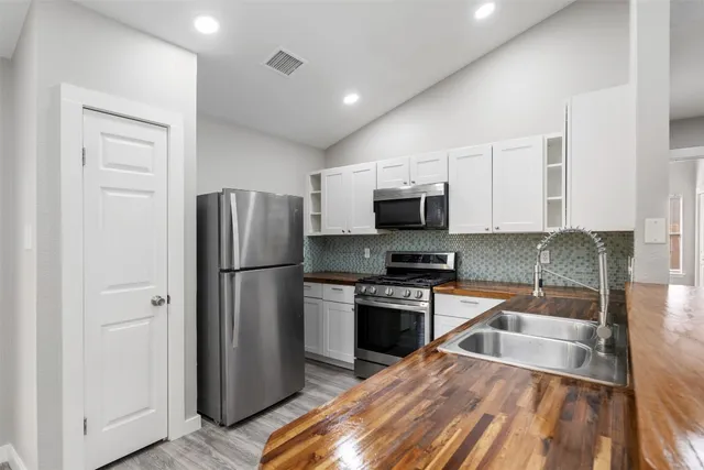 a kitchen with stainless steel appliances a refrigerator and wooden floor