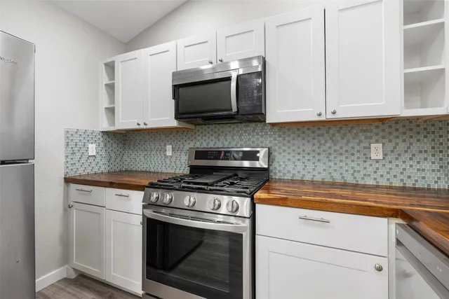 a large kitchen with stainless steel appliances a large counter top a stove and a refrigerator